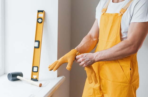 Handwerker in gelber Uniform, der sich auf die Arbeit im Innenbereich vorbereitet. Konzeption der Hausrenovierung