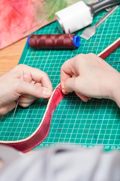 Handwerker näht Gürtel für neue Ledertasche