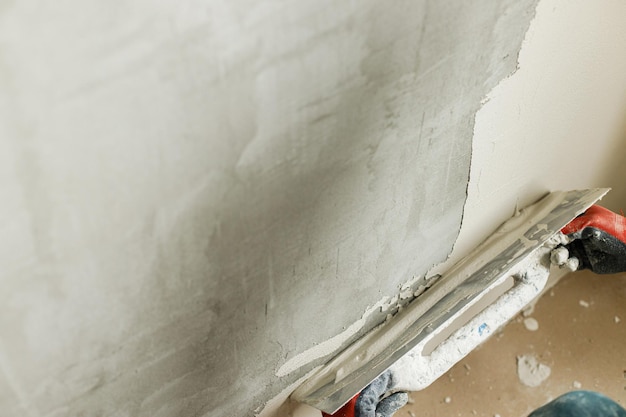 Handwerker verputzt Wände mit Gipsputz und Kelle. Bau eines Hauses und Hausrenovierungskonzept. Nahaufnahme der Arbeiterhände mit Spachtel und Stuck