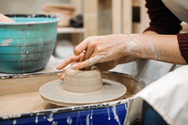 Handwerkerin in der Töpferwerkstatt macht eine Tasse auf einer Töpferscheibe