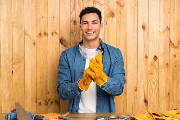 Handwerkermann über dem hölzernen Hintergrund applaudierend