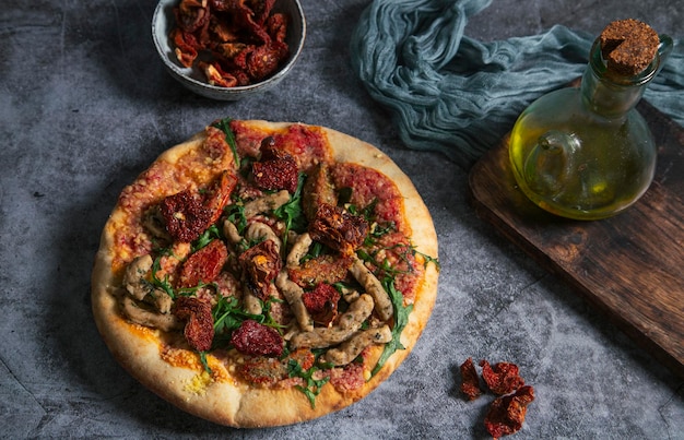 Handwerkliche vegane Pizza mit tofugetrockneten Tomaten und Rucola auf rustikalem Hintergrund