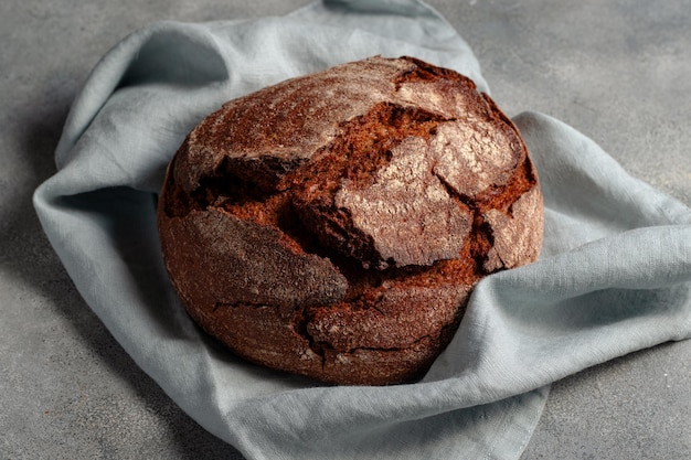 Handwerkliches dunkles ungesäuertes Brot auf grauem Steinhintergrund mit blauer Leinenserviette