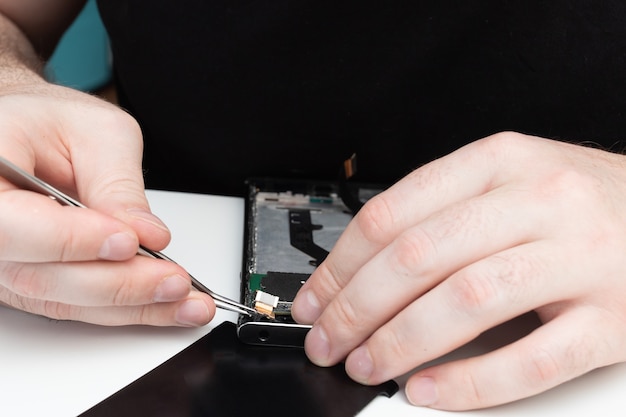 Handy Reparatur. Der Assistent sammelt ein Smartphone aus den Details