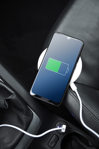 Handy, Smartphone, Handy wird aufgeladen, Akku mit USB-Ladegerät im Auto aufladen. moderne schwarze Autoinnenausstattung.