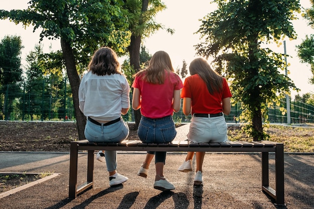 Handy-Sucht-Gruppe junger multiethnischer Mädchen mit Smartphone, die auf einer Bank im Park sitzen