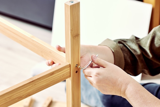 Handyman está montando la mesa con la ayuda de una llave Allen