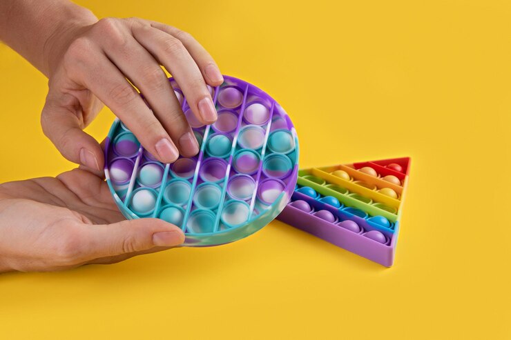 Foto hans femenino usando color redondo popit juguete antistress para niños y adultos en un fondo amarillo