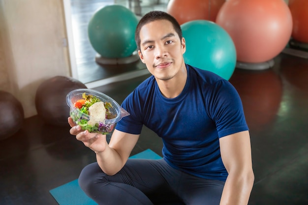 Hansome Asian-Männer mit einer Schüssel Gemüsesalat an der Eignungsturnhalle.