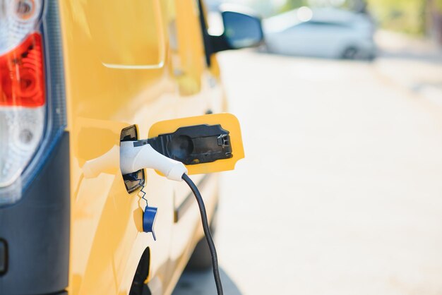 Hansome chico barbudo cerca de su nuevo coche eléctrico moderno en la estación de carga