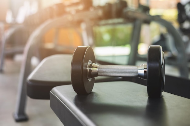 Foto hantel auf der bank im modernen indoor-fitness-hintergrund. fitness-sportclub mit schweren trainingsgeräten für muskulöse.