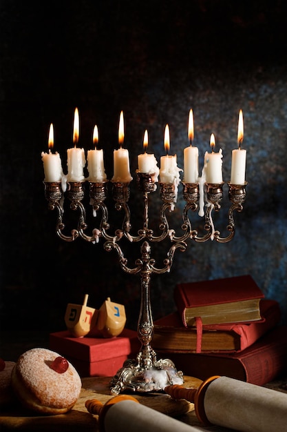 Hanukkah candelabro tradicional rosquilla dreidel libros religiosos Tanakh y pergamino Tanakh en un fondo oscuro