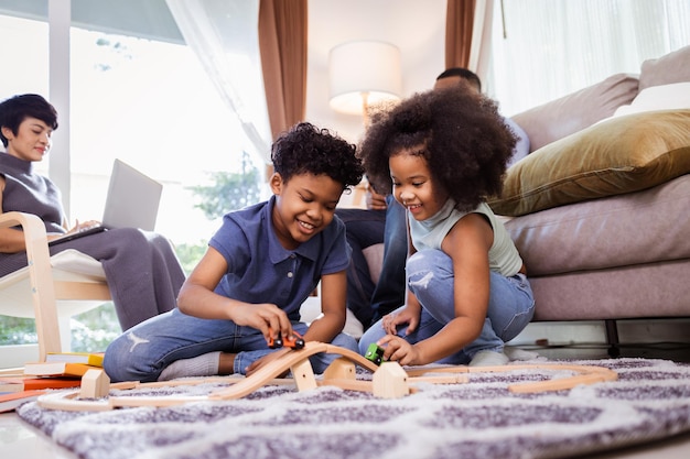 Happy America Africa Family Hijo e hija juegan al juguete en la sala de estar con los padres