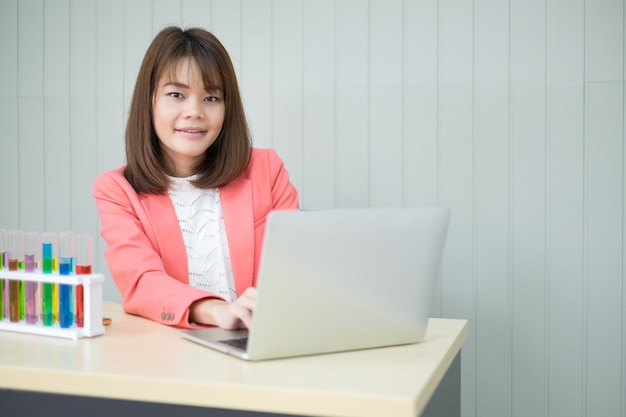 Happy asian woman wear pink suit type documento de trabajo en la computadora portátil