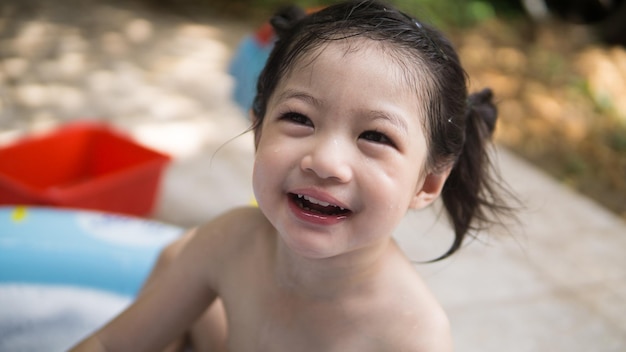 Happy Baby asiatischen Mädchen nehmen ein Bad im Freien mit ihrer Mutter Kind im Freien plantschen in der Badewanne Sweet lächelnd