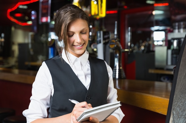 Happy barmaid escrevendo no bloco de notas