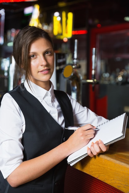 Happy barmaid escrevendo no bloco de notas