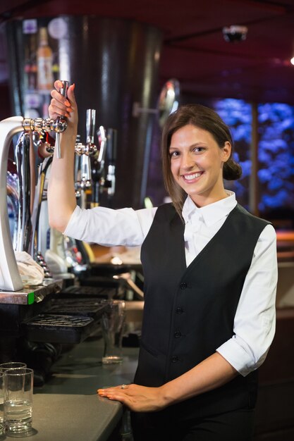 Happy barmaid puxando uma cerveja de cerveja