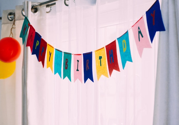 Happy Birthday Banner Party Hintergrund vor weißen Vorhängen und natürlichem Licht