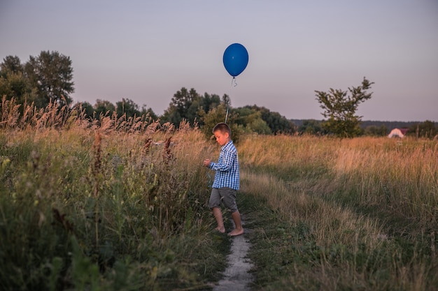 Happy Boy hace sus deseos y sueños al aire libre con globo Hermosa libertad de tarjeta de verano