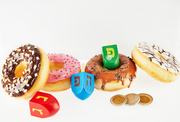 Happy Chanukka und Chanukka Sameach - Traditionelle jüdische Donuts, Kreisel und Chanukka-Geld auf weißem Hintergrund