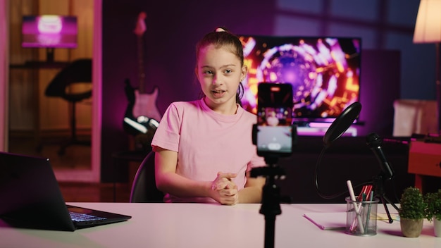 Happy Child filmt Reaktionsvideo für Gen Z Zuschauer bereiten sich darauf vor, Online-Videos auf Laptop-Handkamera aufzunehmen Kleines Mädchen, das Reaktionen auf Internetclips für Social-Media-Kanäle aufnimmt