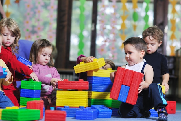 Happy Child Kids Group hat Spaß und spielt im Kindergarten Indoor-Vorschulbildungskonzept mit Lehrer