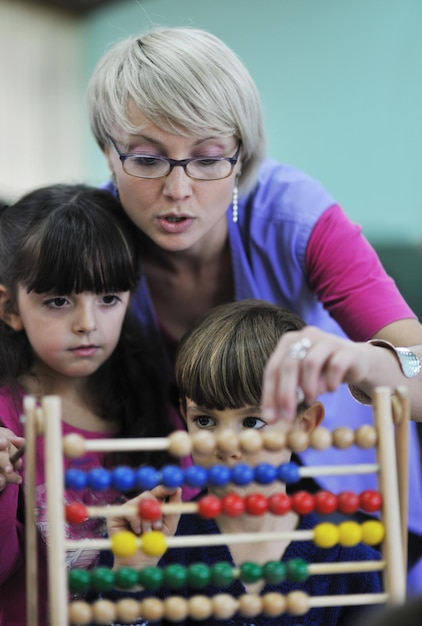 Happy Child Kids Group hat Spaß und spielt im Kindergarten Indoor-Vorschulbildungskonzept mit Lehrer