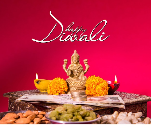 Happy Diwali Grußkarte mit Öllampe oder Diya mit Feuerwerkskörpern, Mithai, Trockenfrüchten, indischen Geldscheinen, Ringelblumenblume und Statue der Göttin Laxmi oder Lakshmi