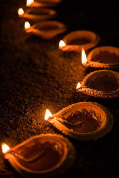 Happy Diwali - muitos diya de terracota ou lâmpadas de óleo dispostas sobre a superfície de argila ou no solo em uma linha ou forma curva ou em zigue-zague, foco seletivo