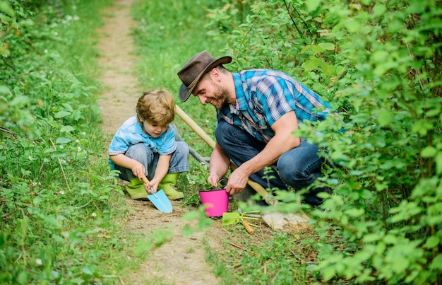 Happy Earth Day Familienstammbaum Pflege Vater und Sohn in Cowboy-Hut auf Ranch Hacke Topf und Schaufel Gartengeräte Öko-Bauernhof kleiner Junge Kind hilft Vater in der Landwirtschaft Gartenbauaktivitäten