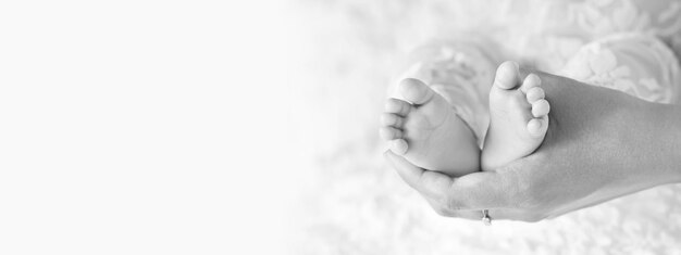 Happy-Family-Konzept Schönes konzeptionelles Bild der Mutterschaft Babyfüße in Mutterhänden Nahaufnahme Mutter und ihr Kind Schwarz-Weiß-Bild Banner-Kopierraum