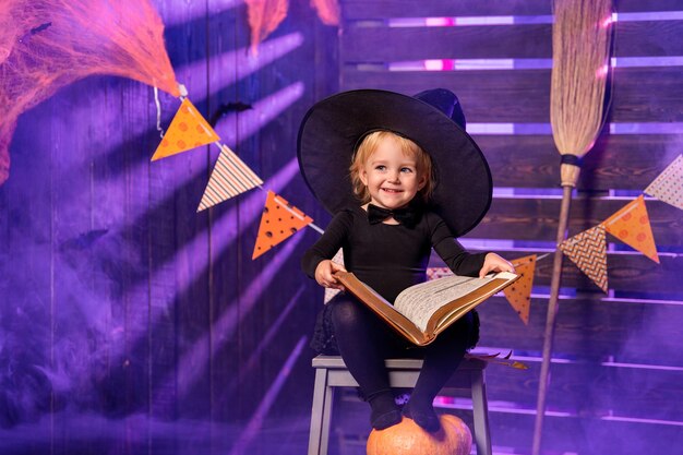 Happy Halloween Süße fröhliche kleine Hexe mit Zauberstab und Zauberbuch zaubert