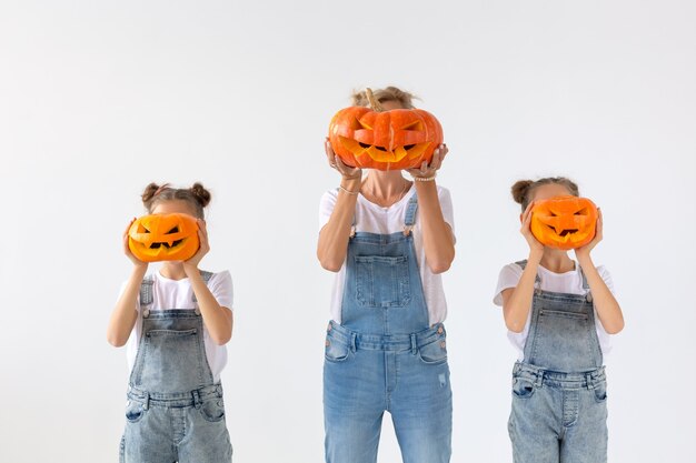 Happy Halloween und Feiertagskonzept - Eine Mutter und ihre Töchter mit Kürbissen. Glückliche Familie, die sich auf Halloween vorbereitet.