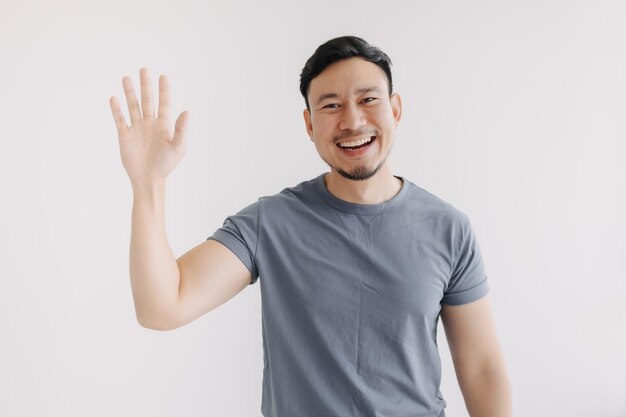 Foto happy hombre asiático saltar para saludar y decir hola de pie aislado en blanco