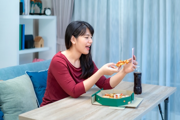 Happy hour virtual de mulher asiática, encontrar o jantar e comer comida de pizza on-line junto com o namorado em videoconferência com tablet digital