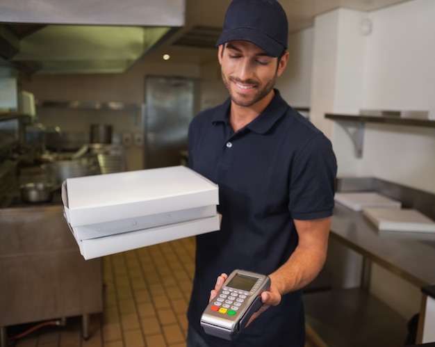 Happy pizza delivery man holding máquina de tarjeta de crédito