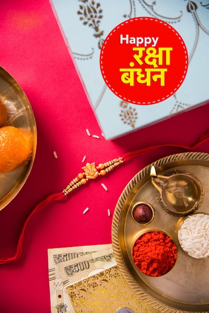Happy Raksha Bandhan oder Rakhi Grußkarte mit Designergarn, Diya, Pooja Thali, Geschenkbox, indischen Banknoten und Süßigkeiten usw. Stimmungsvolle Beleuchtung, selektiver Fokus