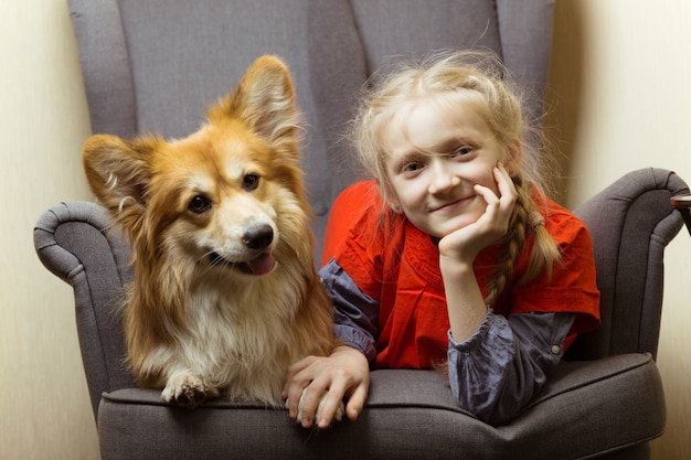 Happy - schönes blondes Mädchen und flauschiger Hundecorgi haben Spaß beim Posieren für die Kamera