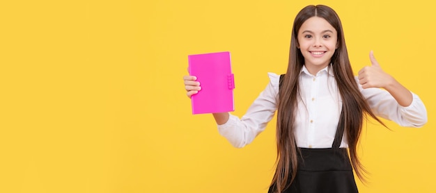 Happy Teen Girl in Schuluniform schlagen Buch Daumen nach oben Porträt von Schulmädchen Student Studio Banner Header Schulkind Gesicht copyspace