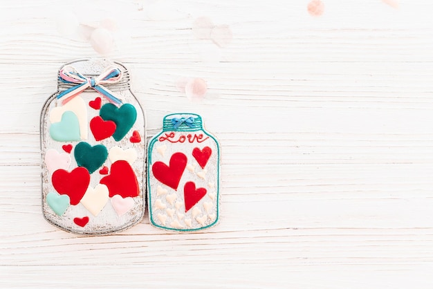 Happy Valentine's Day Grußkartenglas mit bunten Plätzchenherzen auf weißem rustikalem Holzhintergrund mit Konfetti flach lag Platz für Text Mockup Happy Mother's Day oder Women's