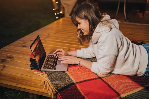 Happy Woman Freelancer mit einem Laptop auf einem gemütlichen Glamping-Zelt an einem Sommerabend Luxus-Campingzelt für Outdoor-Urlaub und Urlaub Lifestyle-Konzept