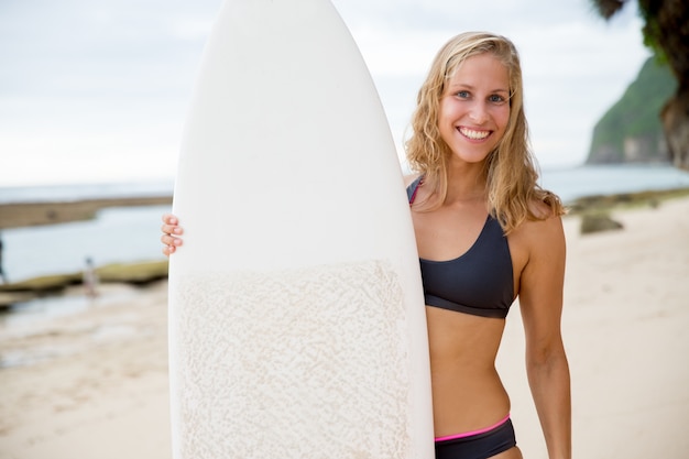 Happy Woman Standing von Surfboard am Strand