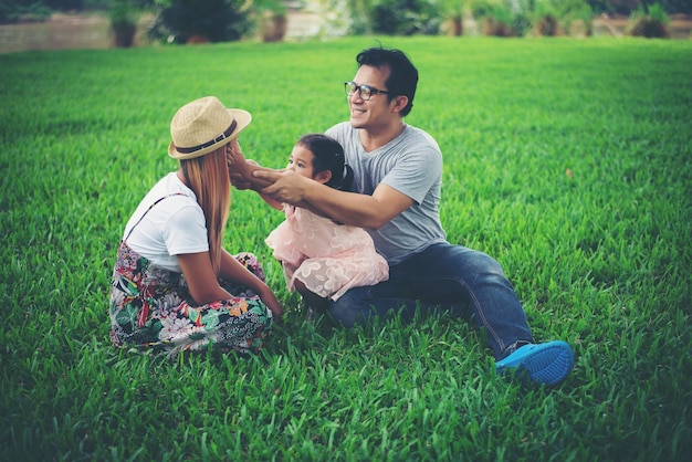 Happy young family passando o tempo no parque, pai mãe e filha brincando na grama