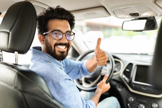 Foto happy young indian guy businessman buying car gesturing thumb up