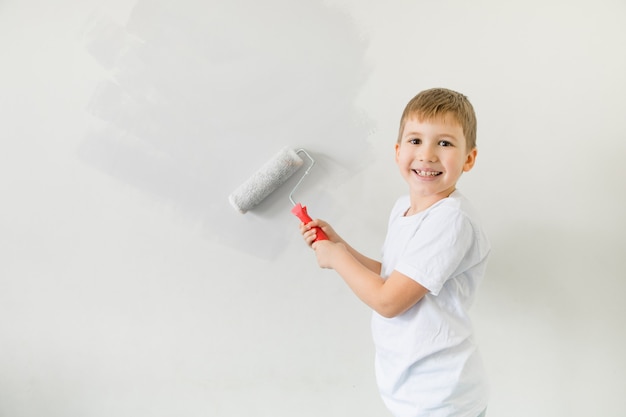 Happysmoling criança criança criança pintando parede ... o conceito de mudar para um novo apartamento. menino bonitinho pintando a parede do quarto dele.