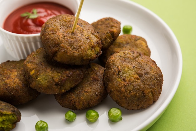 Hara Bhara Kabab o Green Peas Pakora, popular plato indio servido en un plato con salsa picante de tomate y menta sobre un fondo de mal humor. Enfoque selectivo