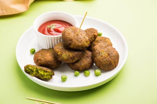 Hara Bhara Kabab oder Green Peas Pakora, beliebtes indisches Vorspeisenessen, serviert in einem Teller mit Tomaten- und Minz-Chutney über stimmungsvollem Hintergrund. Selektiver Fokus