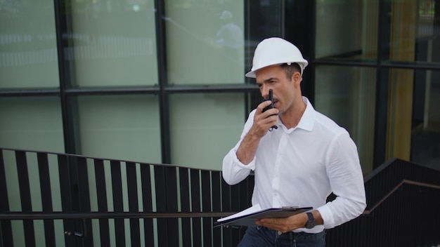 Hardhat-Ingenieur geht nach oben und diktiert eine Nachricht in der Stadt.