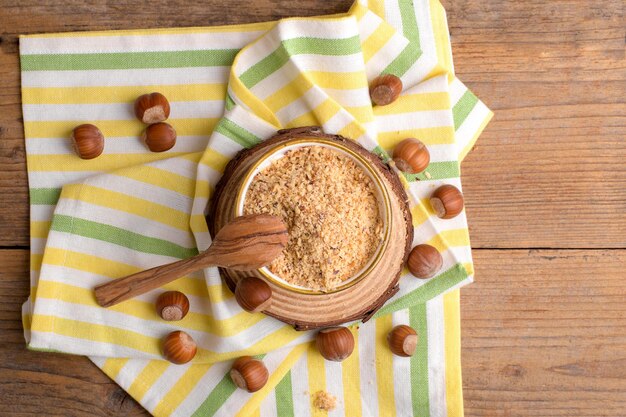 Harina de avellana molida orgánica cruda en un tazón con nueces enteras sobre fondo de madera rústica Harina de nuez alternativa